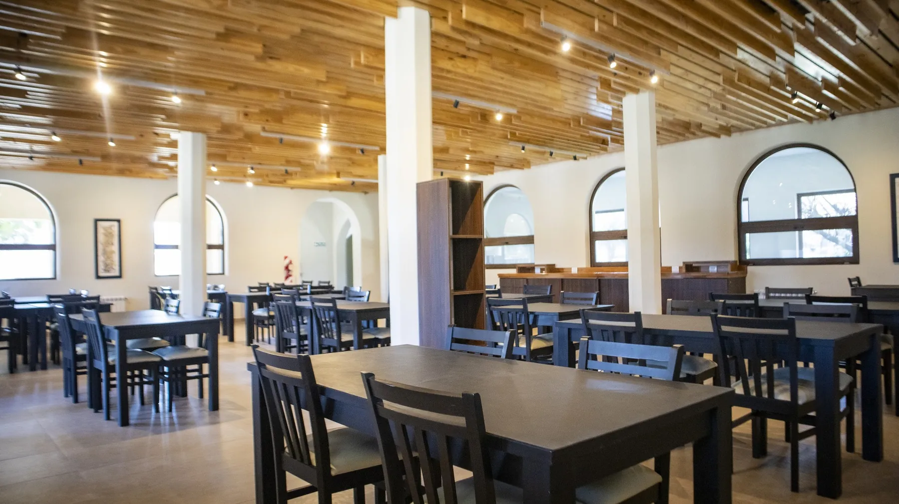 Comedor amplio con techo de madera y ventanales en arco