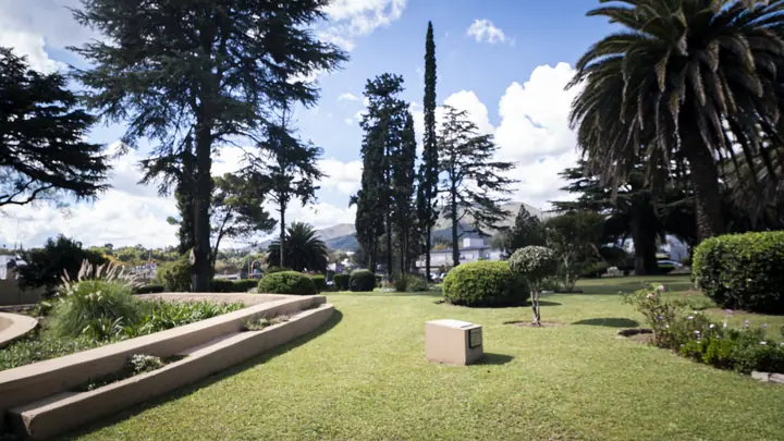 Parque con cedros, cipreses y palmeras, con las sierras de fondo